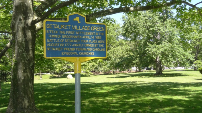 A photo of the blue historical marker on the present-day Setauket Green.